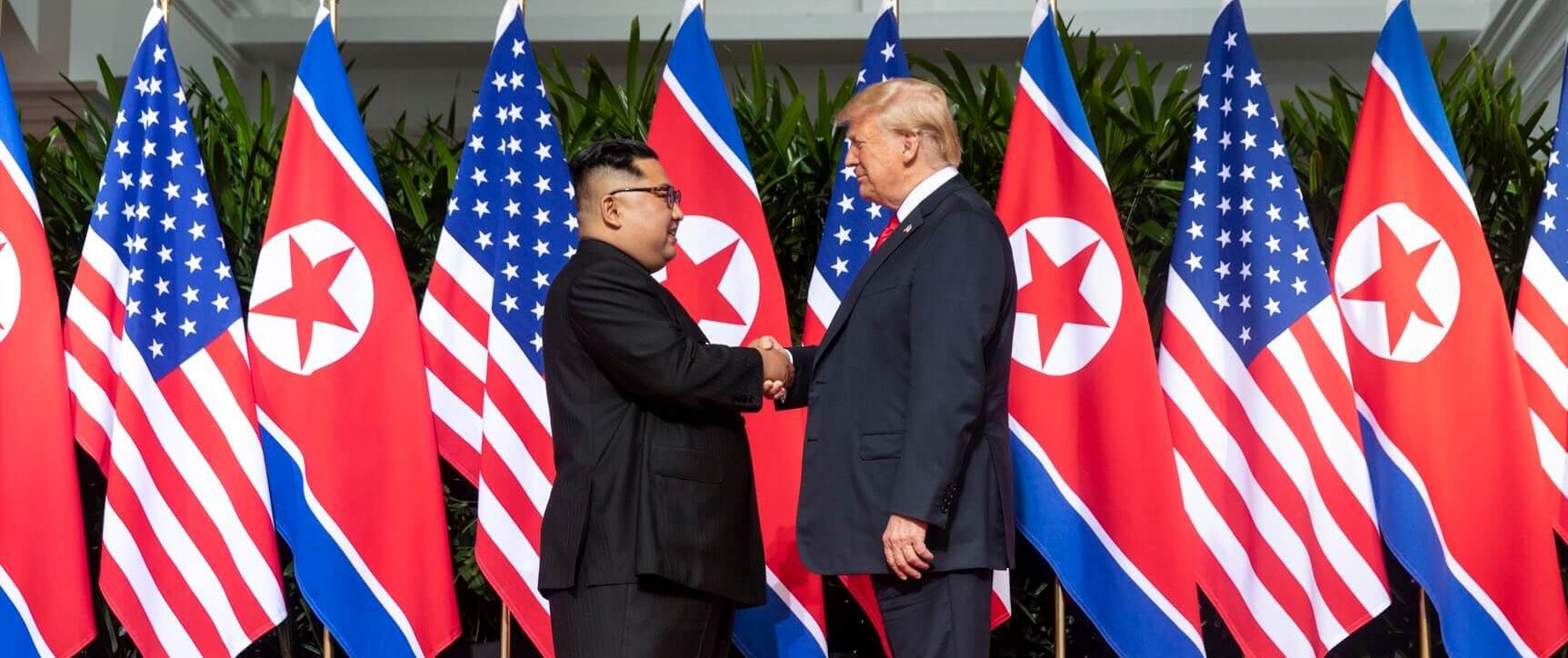 Kim and Trump shaking hands at the red carpet during the DPRK–USA Singapore Summit e1599132464464